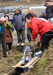 写真＝伏見工業高校生のホイール水車での実演を見学する住民