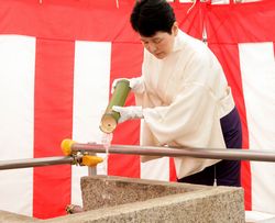 聖地の水を井戸へと注ぐ出口教主